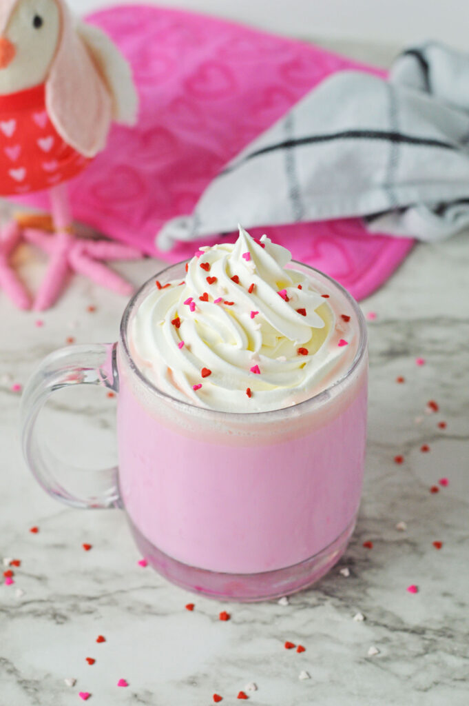 pink hot chocolate topped with whipped cream and heart sprinkles
