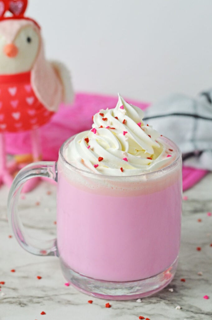 pink hot chocolate topped with whipped cream and heart sprinkles
