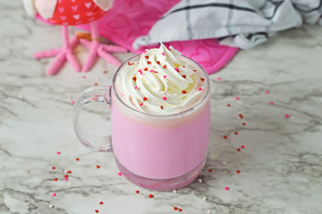 pink hot chocolate topped with whipped cream and heart sprinkles