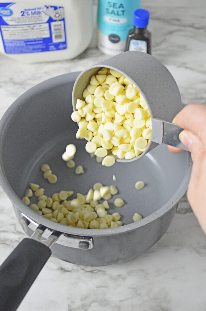 white chocolate chips pouring into a sauce pan