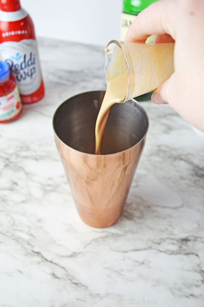 Baileys pouring into a cocktail shaker
