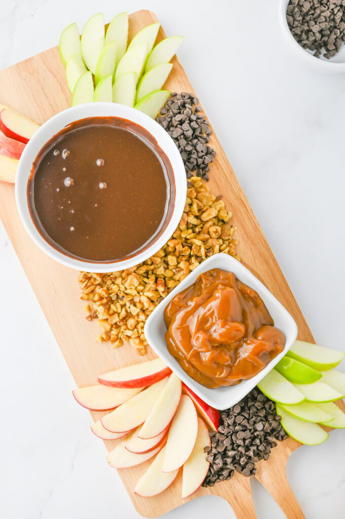 more apples and toppings added to the caramel apple charcutrie board