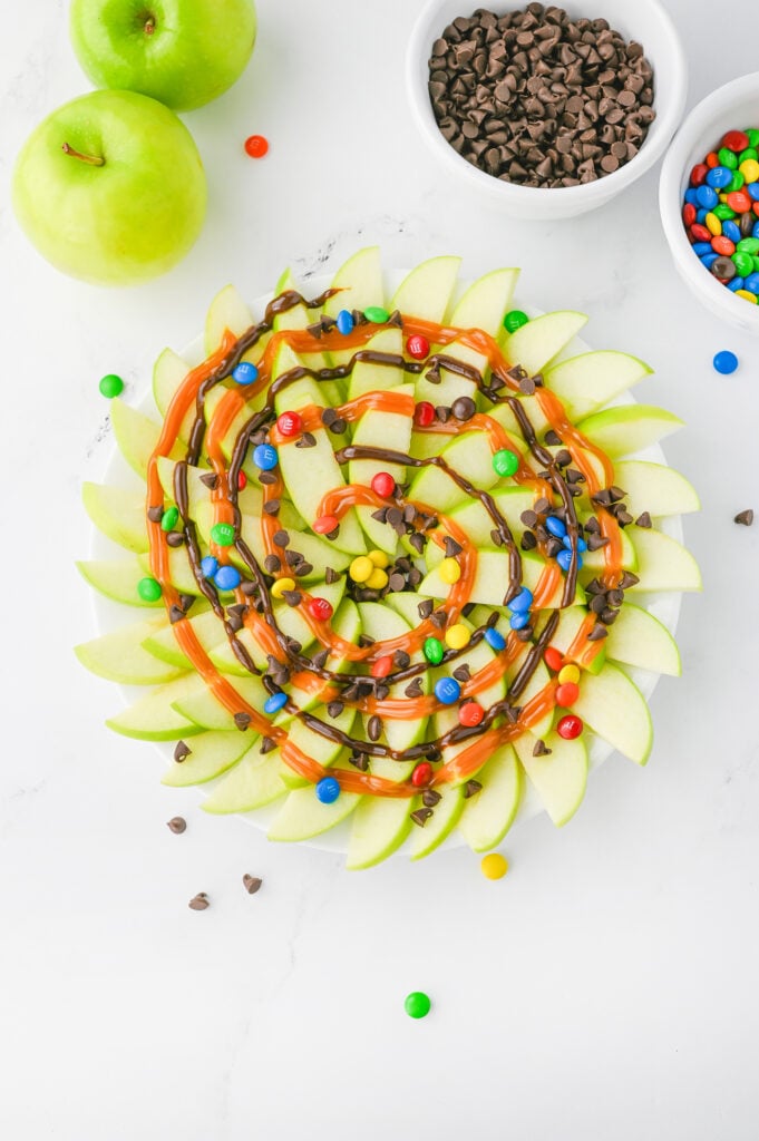 caramel apple nachos- granny smith apples fanned out, and drizzed with chocolate and caramel sauce, topped with mini chocolate chips & M&Ms