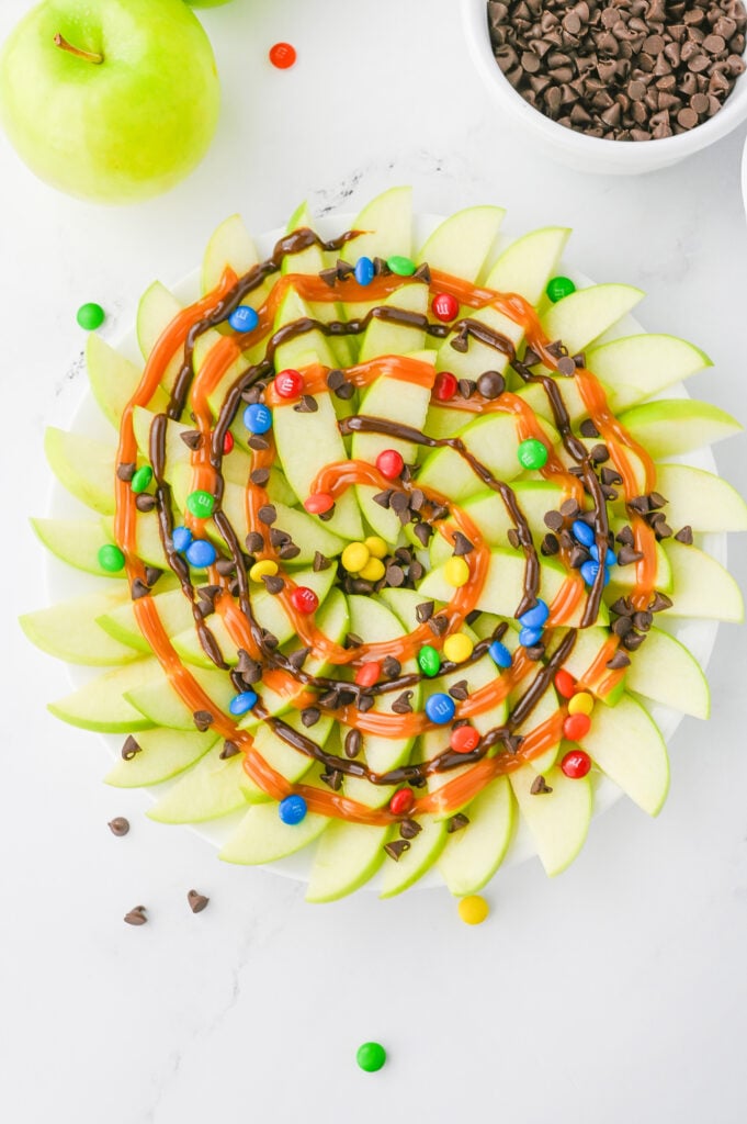 caramel apple nachos- granny smith apples fanned out, and drizzed with chocolate and caramel sauce, topped with mini chocolate chips & M&Ms