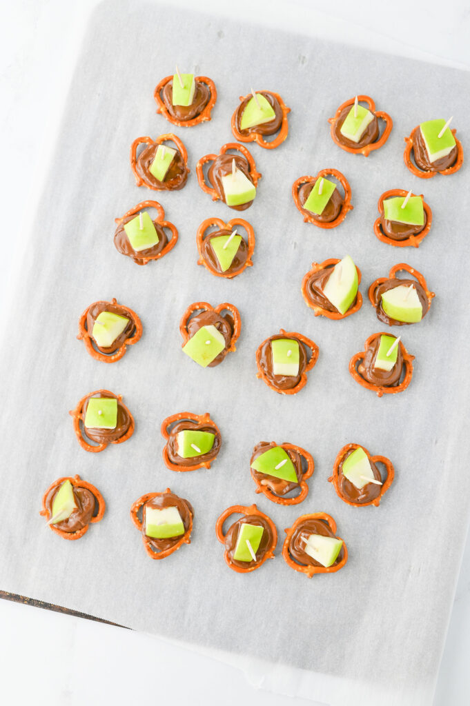 Apple chunks and toothpicks on top of the melted Rolo pretzel candies