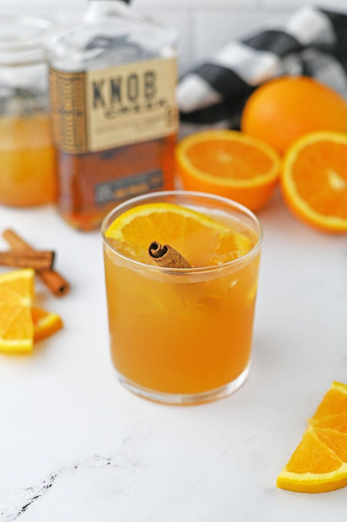 a maple cider old fashioned garnished with an orange slice and a cinnamon stick