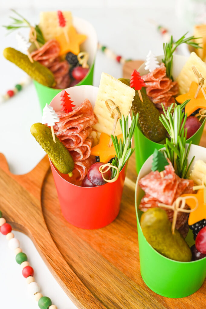 Close up of filled Charcuterie cups showing salami, cheese stars, fruit, and herbs.