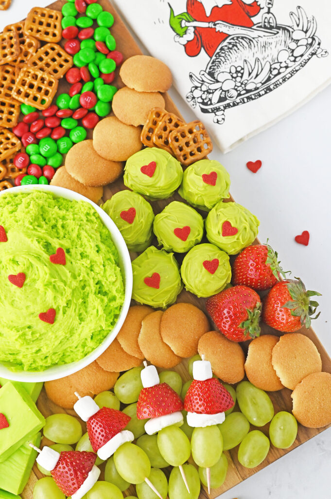 Grinch Oreo balls with red heart candies clustered on the board.