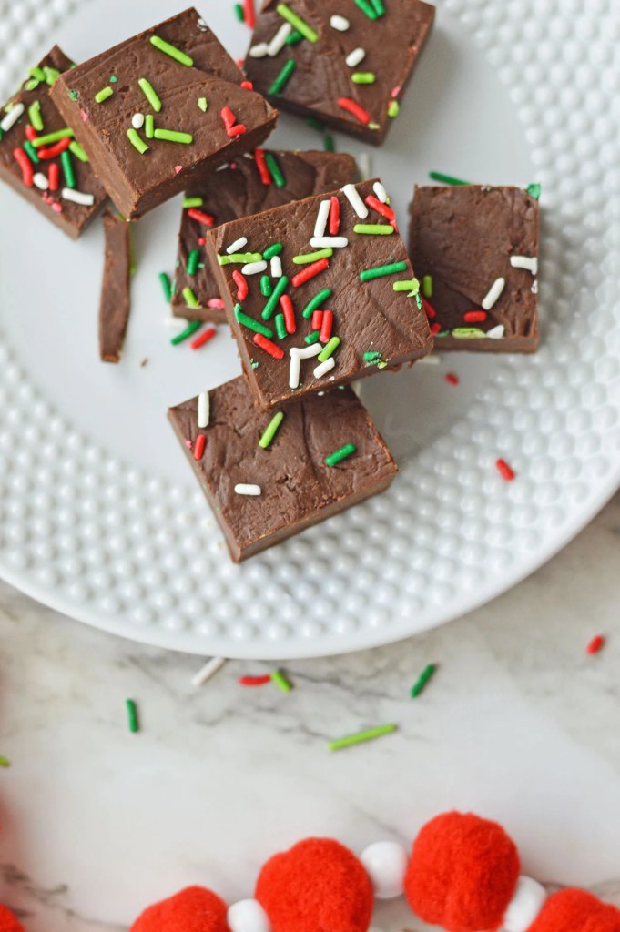 Rich homemade chocolate fudge with colorful Christmas sprinkles on top.