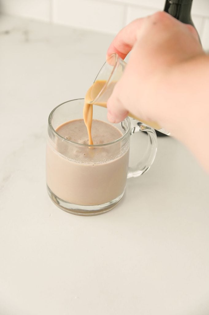 Adding Baileys Irish Cream to a mug of prepared hot chocolate.
