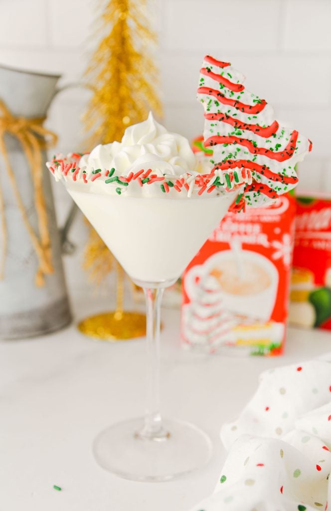 Creamy Christmas Tree Cake Martini topped with whipped cream and a Little Debbie Christmas Tree Cake.