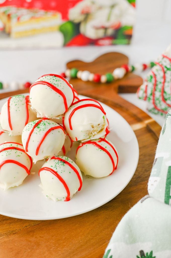 Easy no-bake Christmas Tree Cake balls covered in white chocolate and festive red and green decorations.