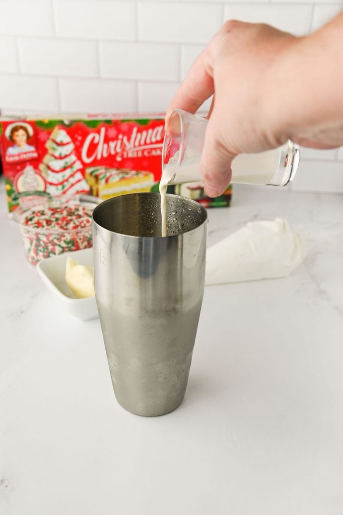 Pouring Christmas Tree Cake creamer into the cocktail shaker.
