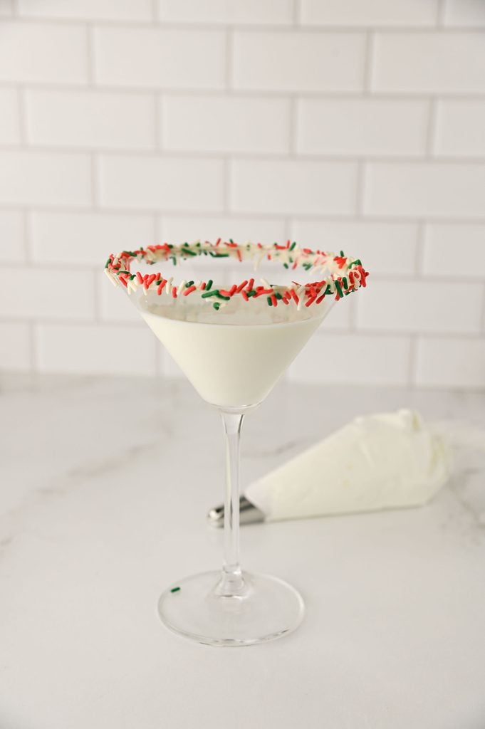 Christmas Tree Cake Martini in a martini glass with a red and green sprinkle rim.