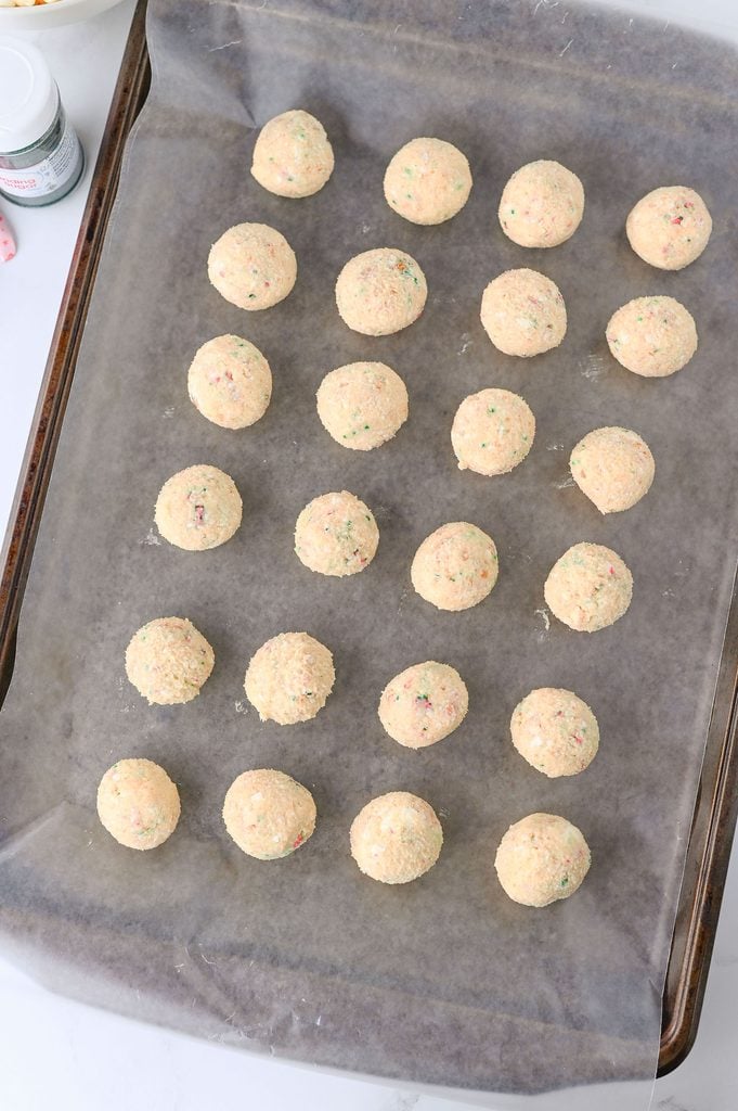 Rolled Christmas Tree Cake Truffle balls arranged on a parchment-lined baking sheet.