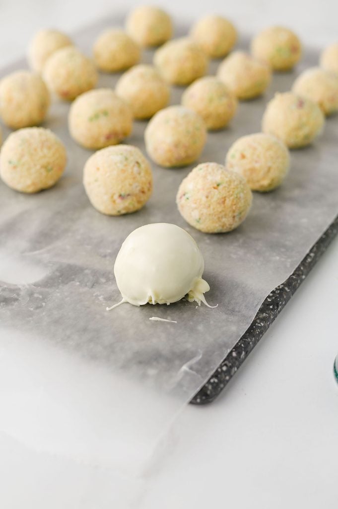 Christmas Tree Cake Truffle being coated in melted white chocolate.