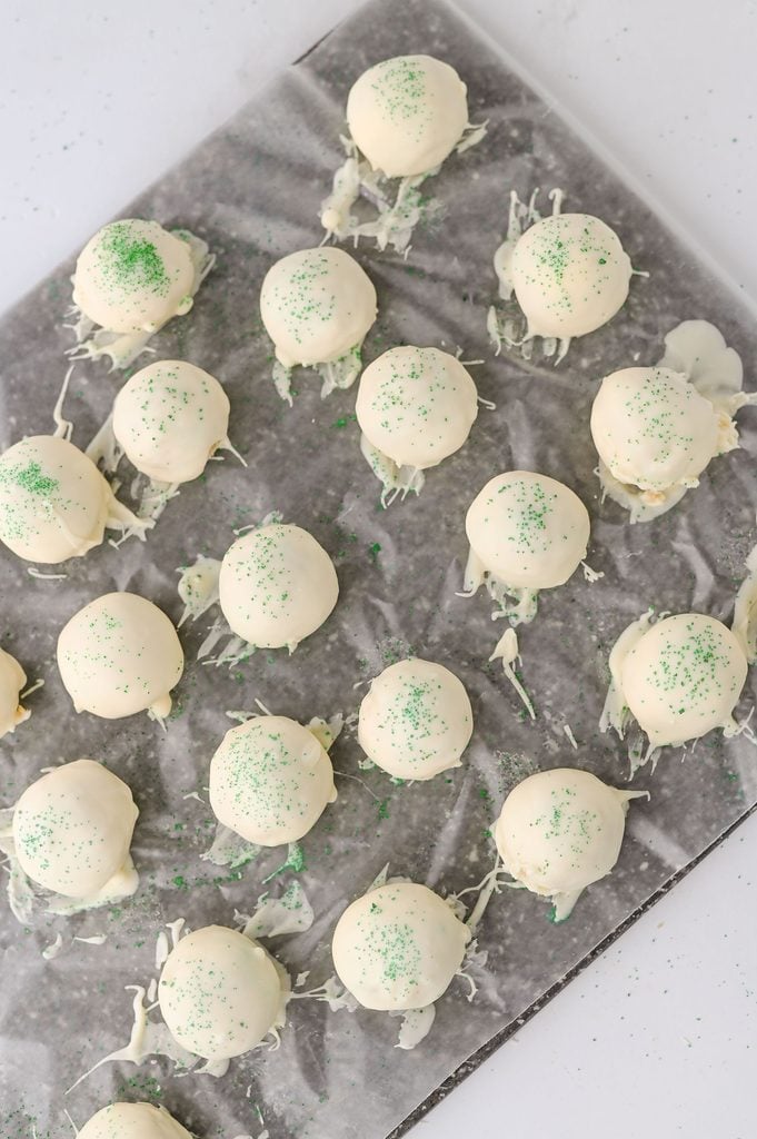 White chocolate-covered Christmas Tree Cake Truffles topped with green sanding sugar.