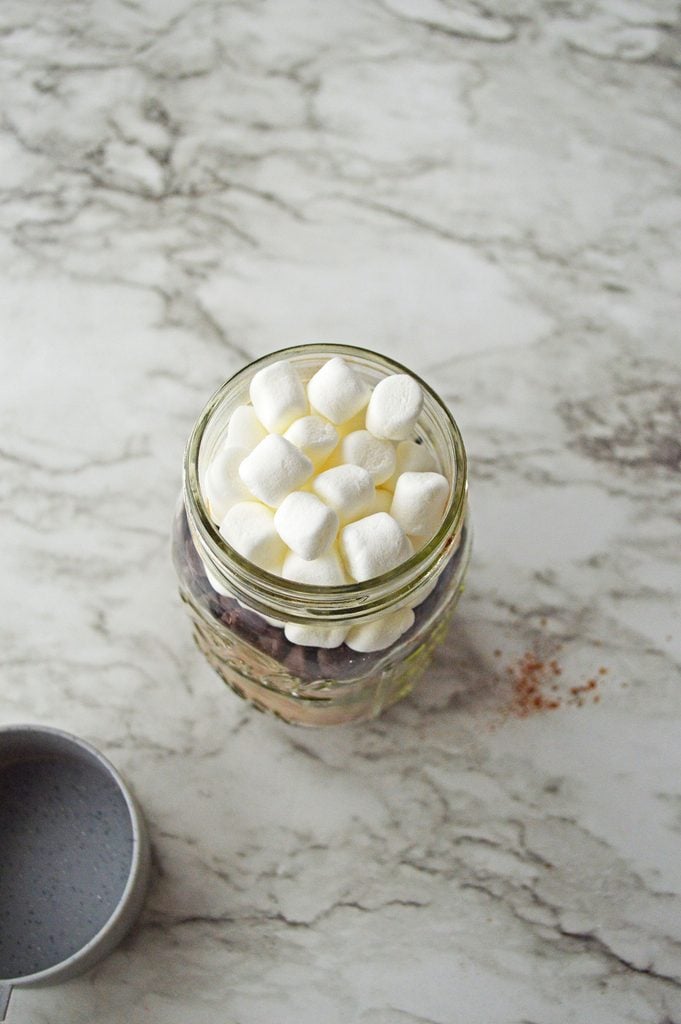 Mini marshmallows added on top of chocolate chips in a homemade hot cocoa gift jar