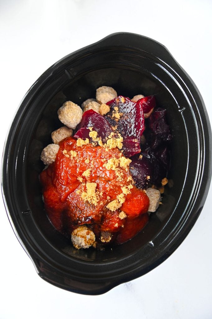 Meatballs and cranberry sauce ingredients added to a slow cooker before cooking