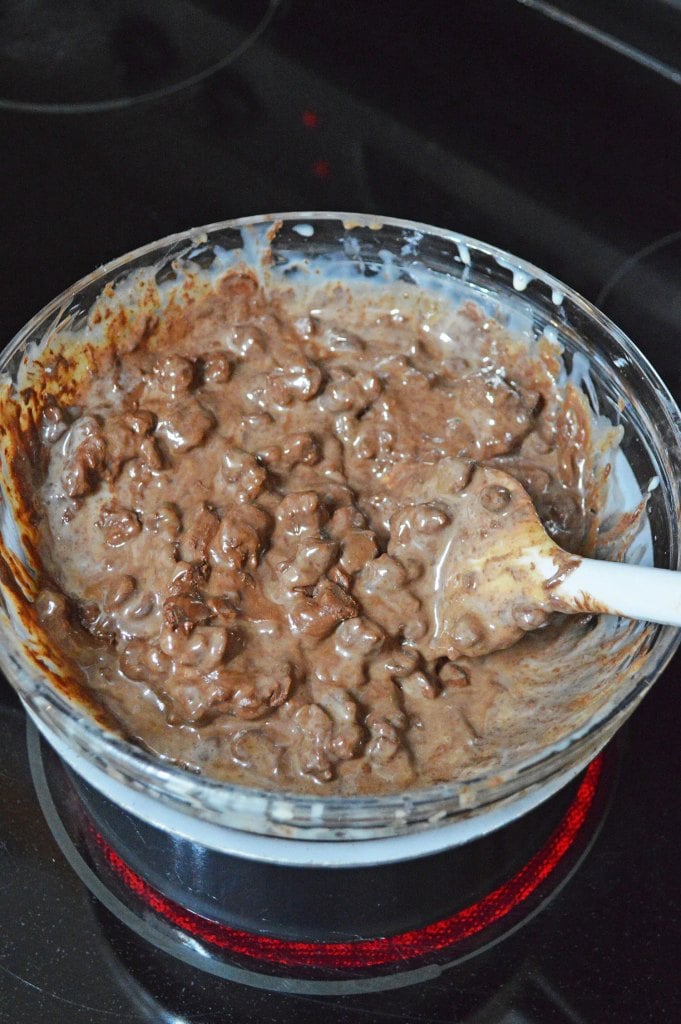 Chocolate fudge mixture being stirred until smooth and creamy.