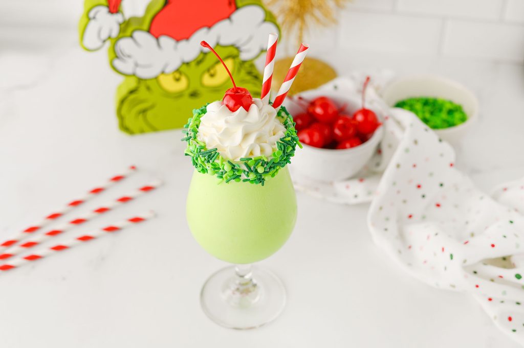 Two green milkshakes with sprinkle-covered rims and whipped cream