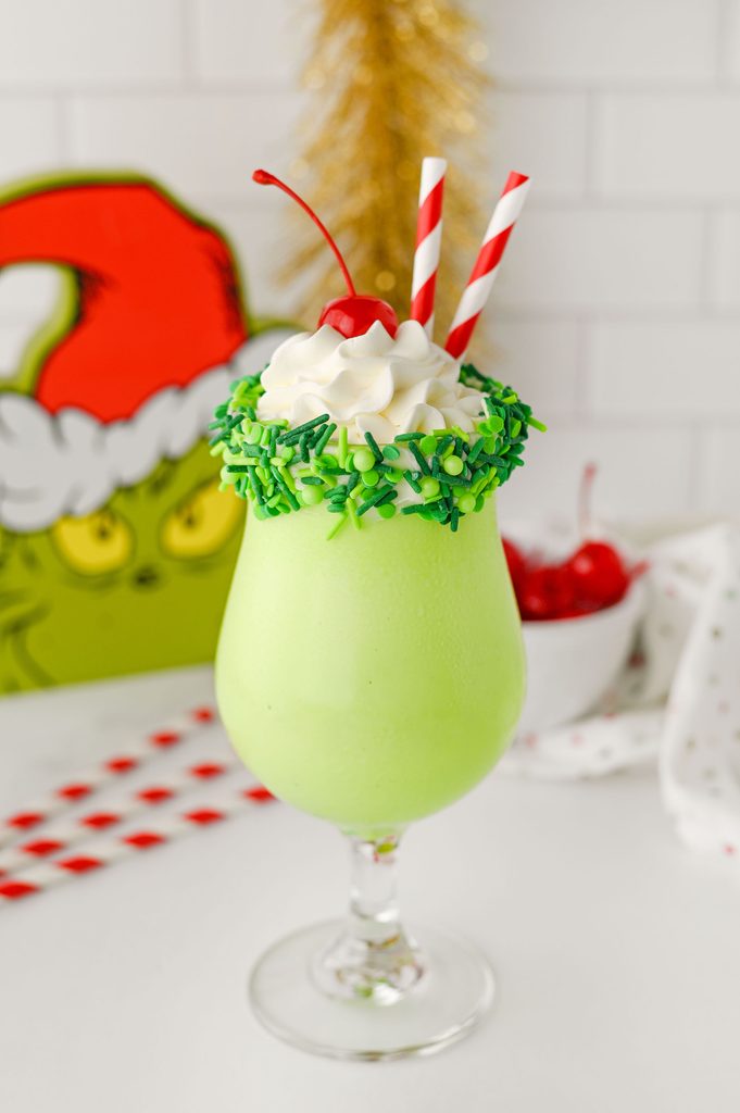 Bright green milkshake topped with whipped cream and a maraschino cherry