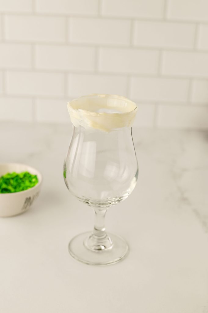 Frosting being spread around the rim of a milkshake glass