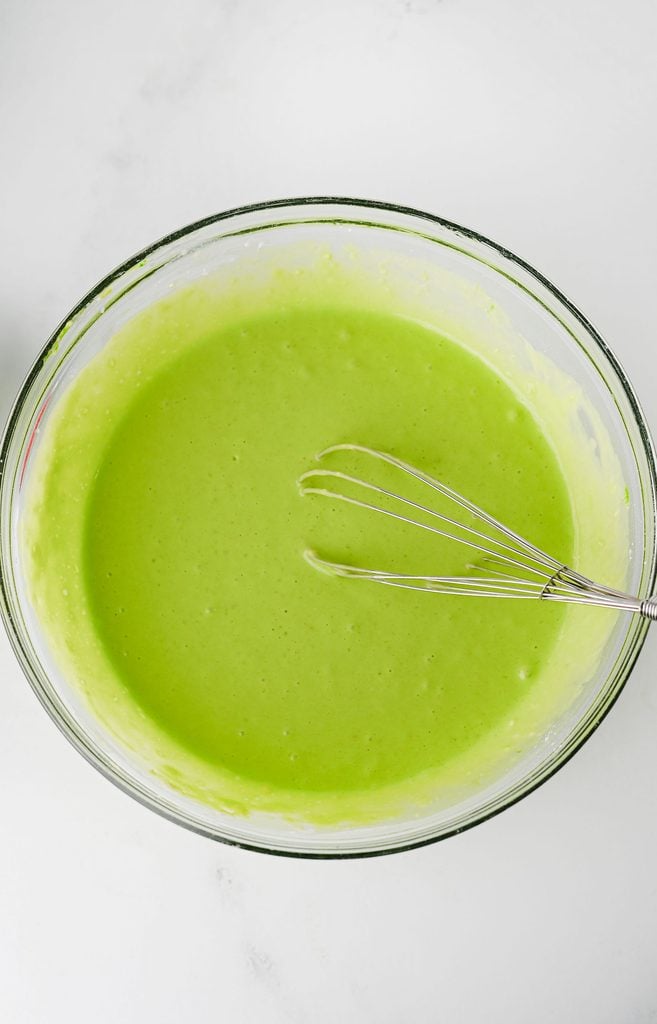 Bright green Grinch pancake batter mixed together in a large bowl.