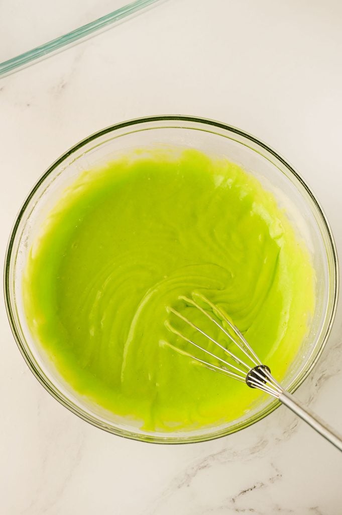 Neon green cake batter mixed to make Grinch Poke Cake.