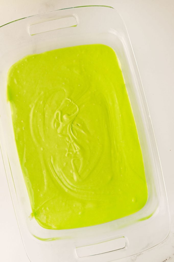 Bright green cake batter poured into a rectangular baking dish before baking.