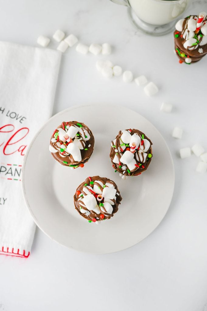 Homemade hot chocolate sticks topped with marshmallows and colorful holiday sprinkles