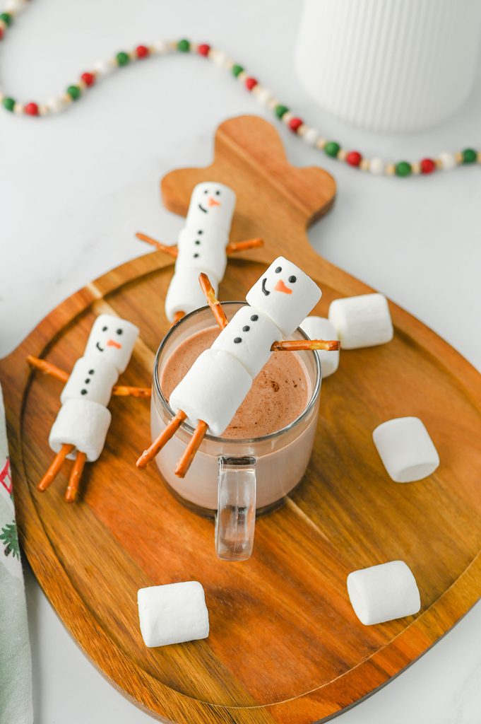 Cup of hot chocolate surrounded by homemade marshmallow snowmen