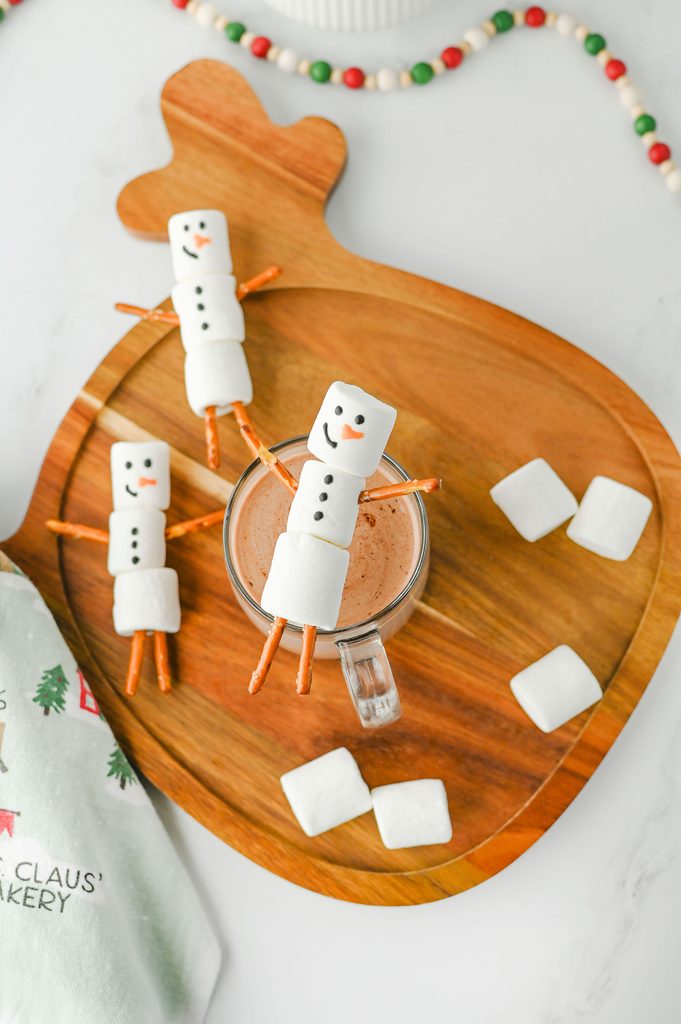 Marshmallow snowman sitting on the edge of a mug of hot chocolate