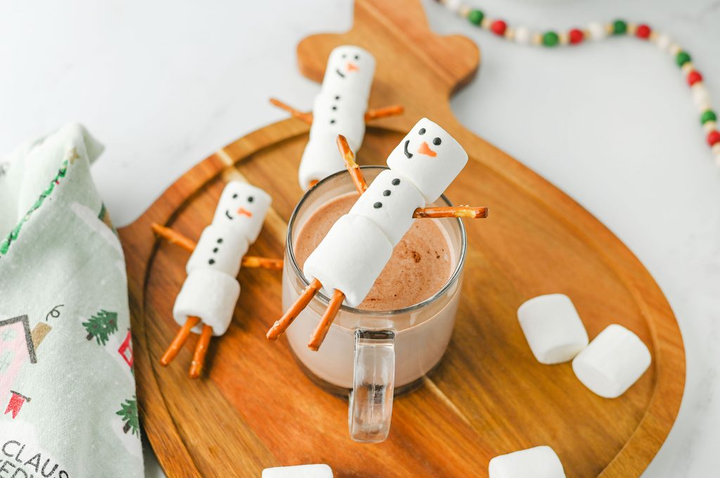 Marshmallow snowmen made with pretzel arms and legs and icing faces