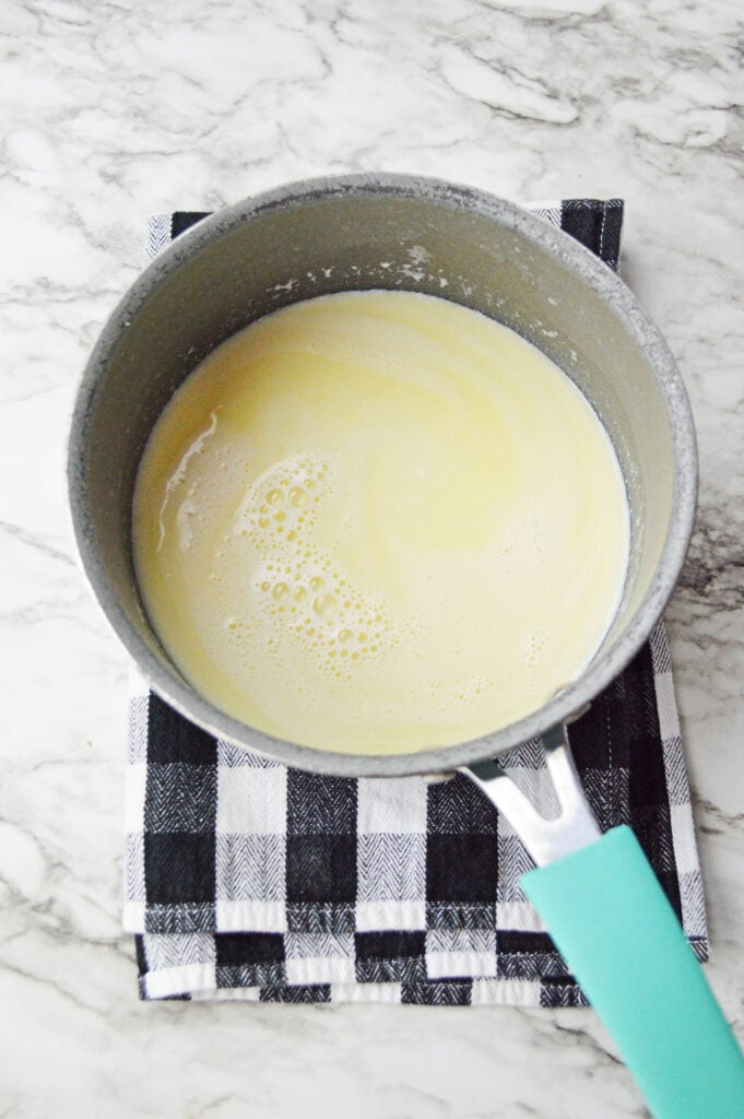Milk, butter, and brown sugar being stirred together in a saucepan to make hot butterbeer.