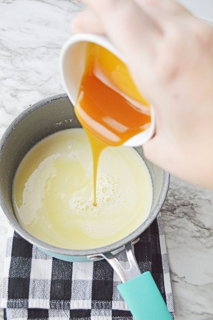 Butterscotch caramel sauce being poured into the warm milk mixture for homemade hot butterbeer.