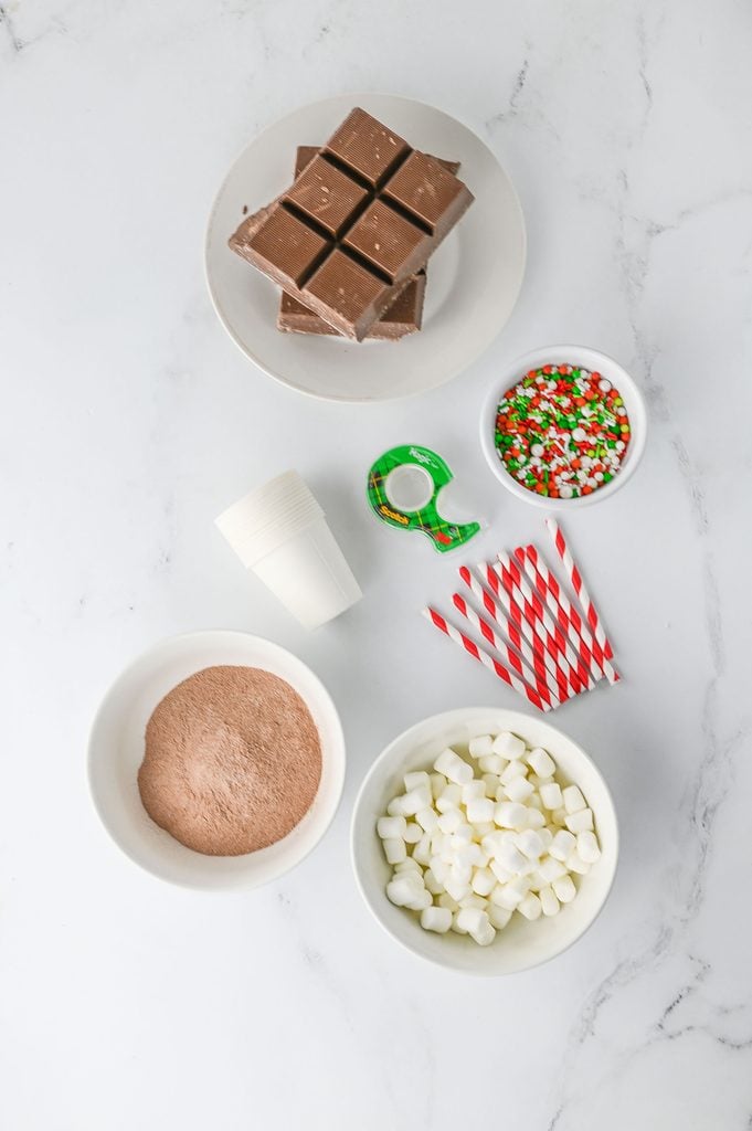 Ingredients for Christmas hot chocolate sticks including chocolate almond bark, cocoa mix, marshmallows, and sprinkles
