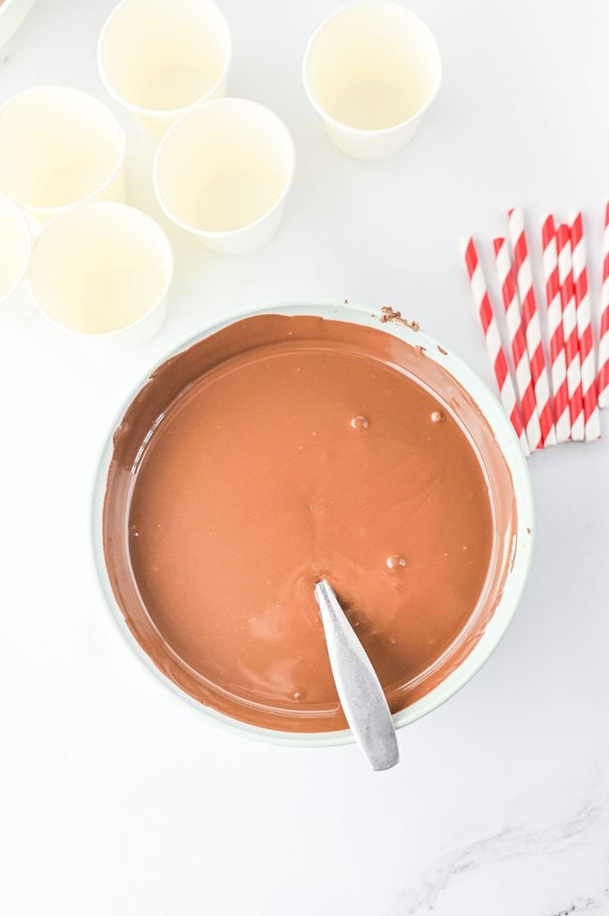 Melted chocolate almond bark in a bowl for making hot chocolate sticks