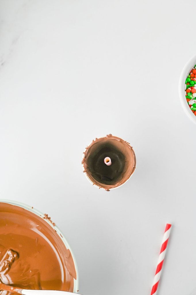 Red paper straws inserted into melted chocolate to create hot chocolate stirrers