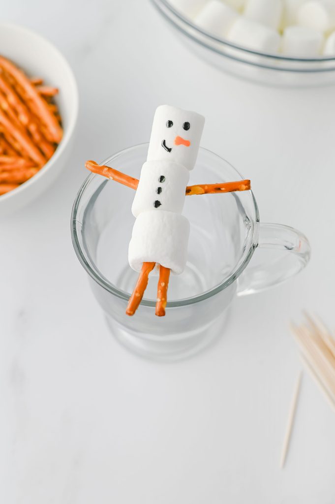 Marshmallow snowman decorated with an icing face, buttons, and carrot nose