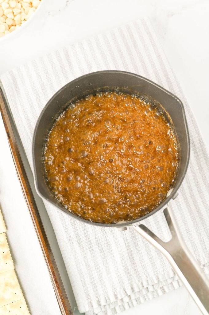 Butter and brown sugar bubbling together in a saucepan to make homemade Christmas crack toffee.