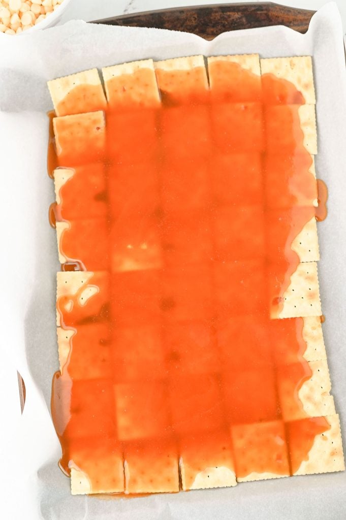 Hot brown sugar toffee mixture poured evenly over saltine crackers before baking.