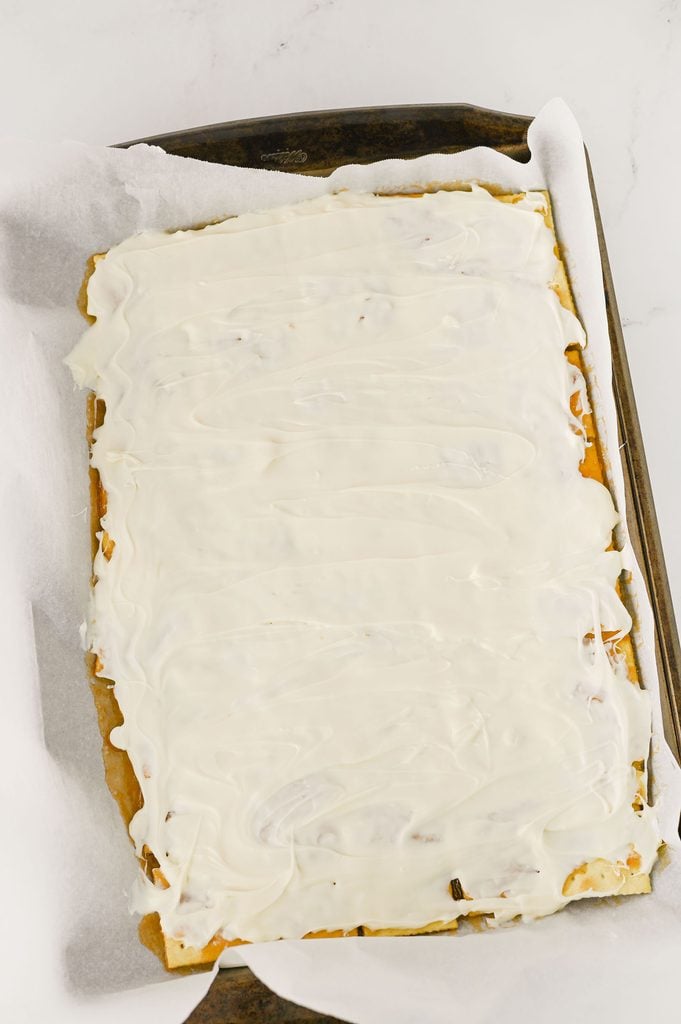 Melted white chocolate spread evenly over the buttery toffee cracker layer.