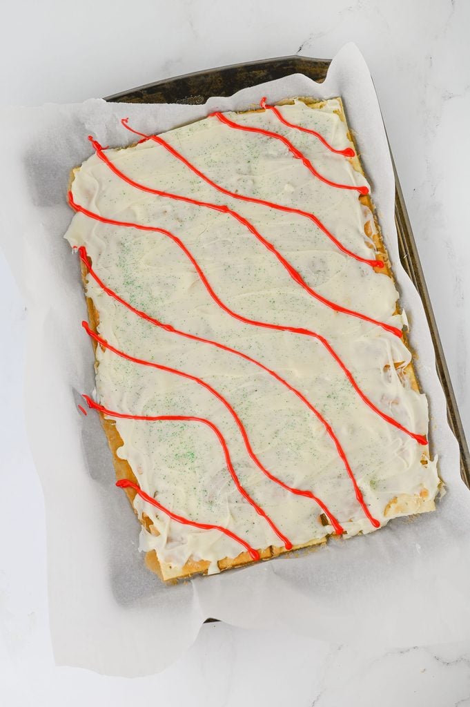 Red cookie icing drizzled in wavy stripes over Christmas Tree Cake Crack.