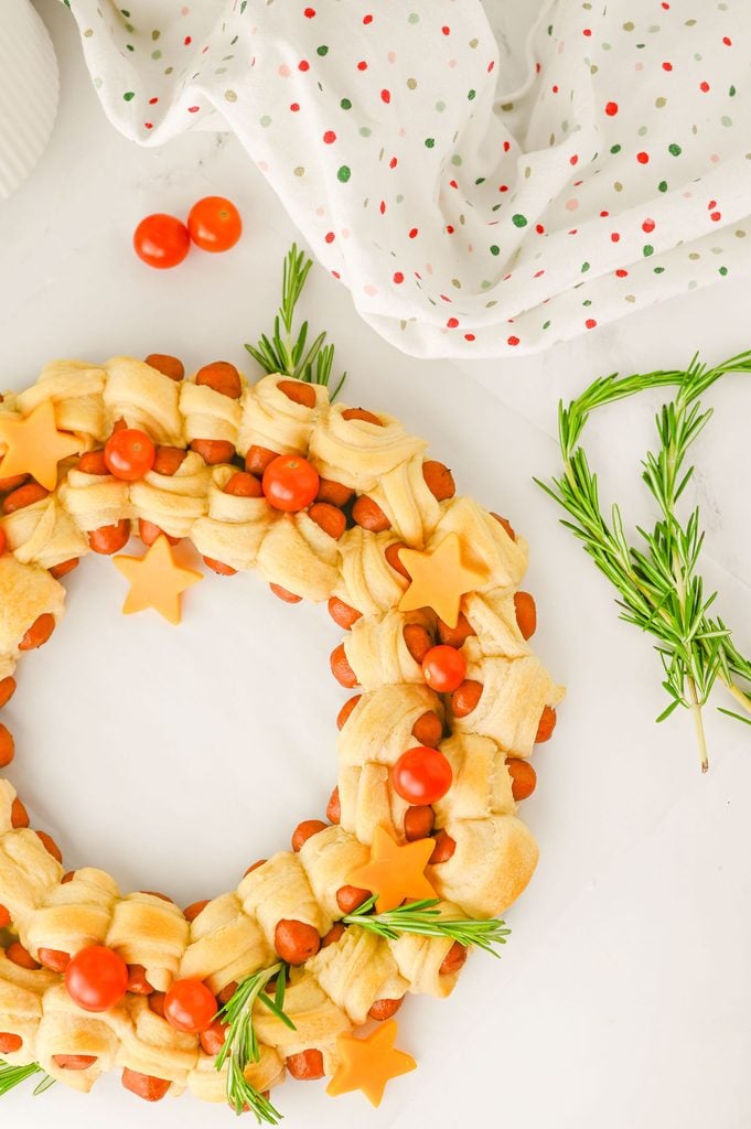 Close-up of golden crescent roll pigs in a blanket arranged into a festive Christmas wreath.