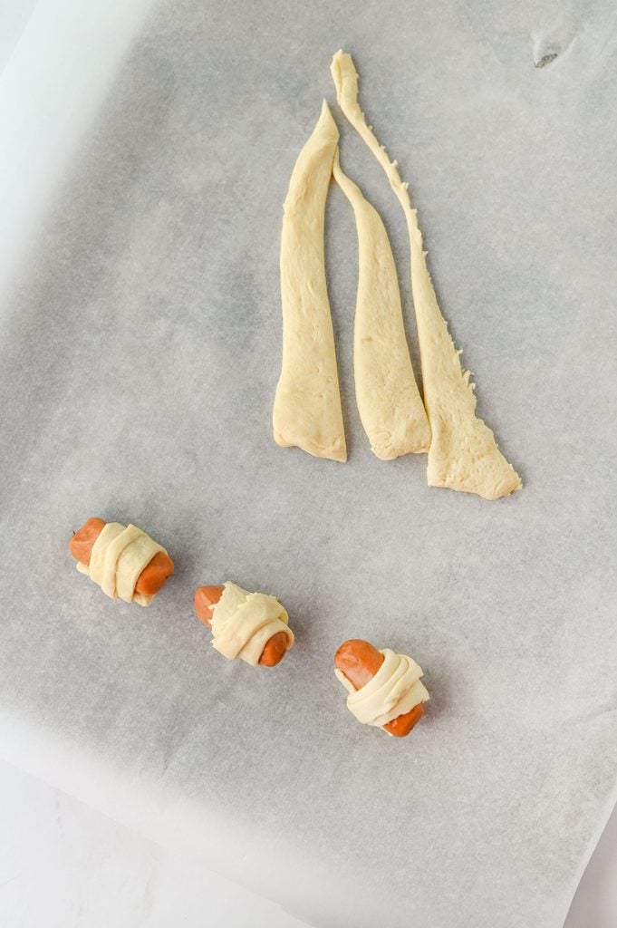 Refrigerated crescent roll dough cut into small triangles for making mini pigs in a blanket.